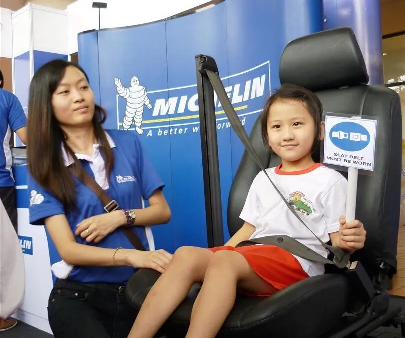 Michelin staff teaching the children on how to wear a seat belt correctly