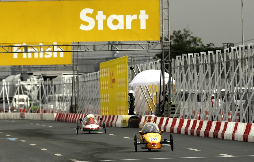The EcoTraveller, #303, a battery electric prototype vehicle from team EcoTraveller at the Institute of Technical Education (ITE) in Singapore, and =The SQU Eco Wheels, #25, a gasoline prototype vehicle from SQU team at the Sultan Qaboos University in Alkhoudh, Oman, run on the track during day two of the Shell Eco-marathon Asia in Manila, Philippines, Friday, March 4, 2016. (Geloy Concepcion via AP Images)
